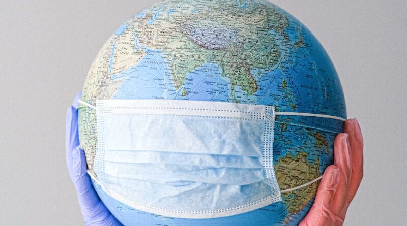 hands with latex gloves holding a globe with a face mask
