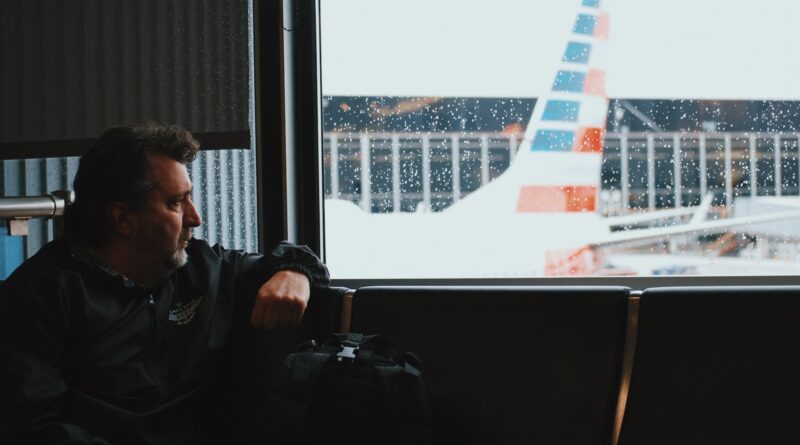 man sitting in airport watching airplane during daytime