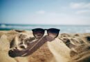 black Ray-Ban Wayfarer sunglasses on beach sand