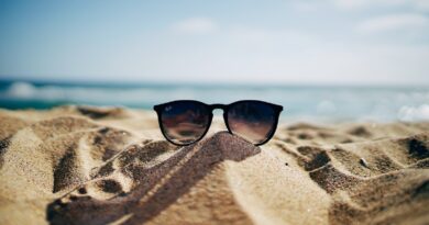 black Ray-Ban Wayfarer sunglasses on beach sand