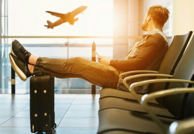 man sitting on gang chair with feet on luggage looking at airplane